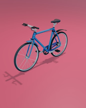 A blue bicycle is positioned against a soft pink background. The design is modern with a sleek frame, featuring black handlebars and seat. Shadows on the surface enhance the three-dimensional look.