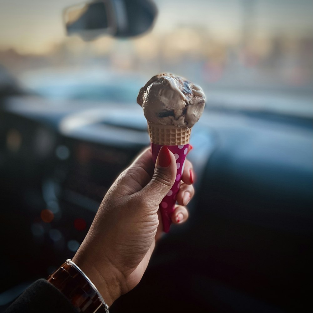 a person is holding an ice cream cone in their hand