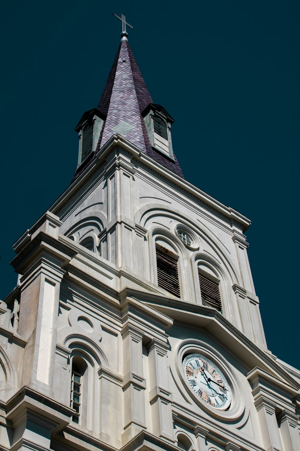 uma grande torre do relógio branco com uma cruz no topo