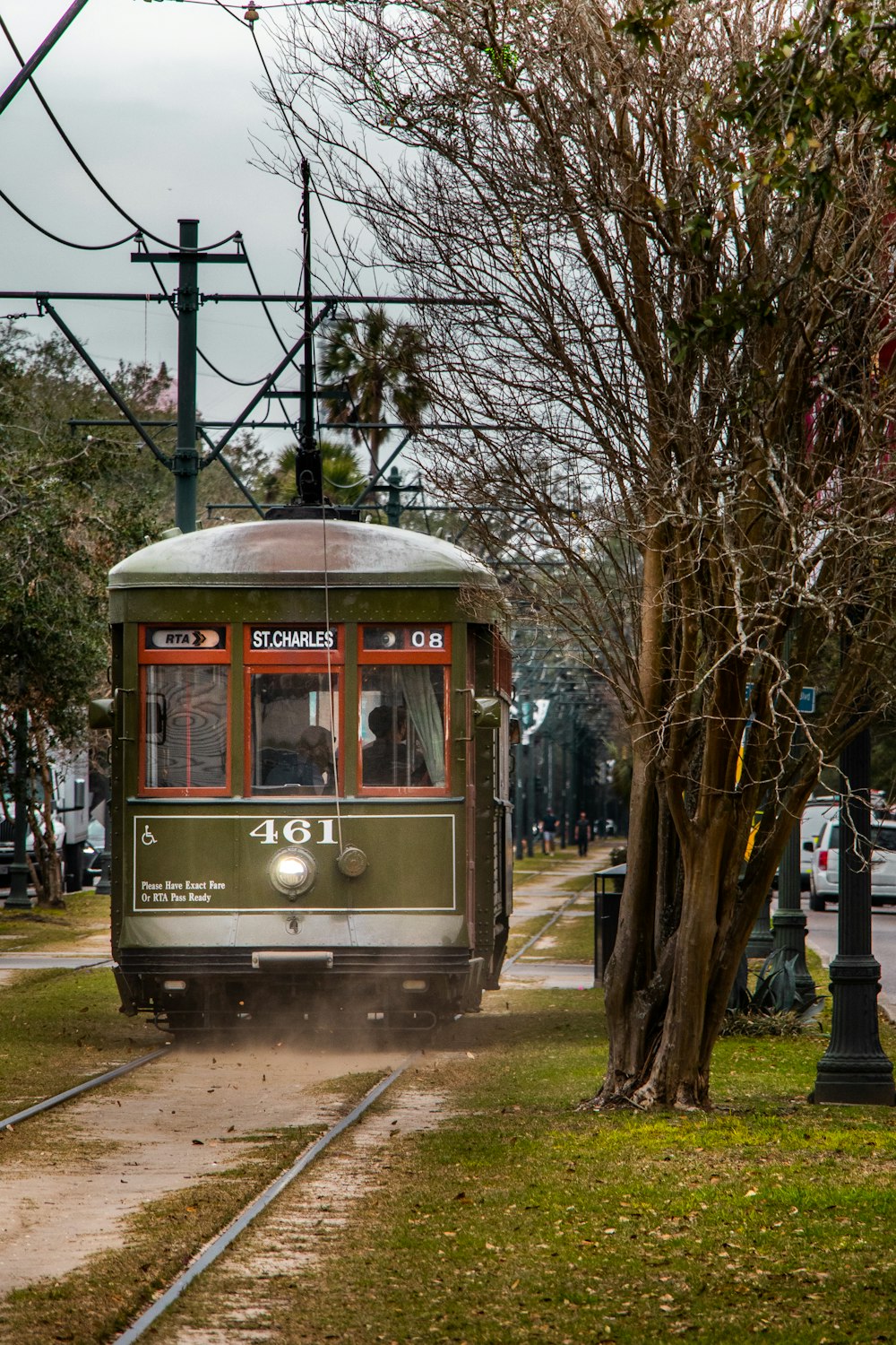 a trolley car traveling down a street next to a tree