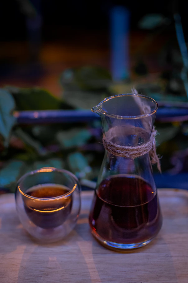 a pitcher of liquid next to a cup of tea
