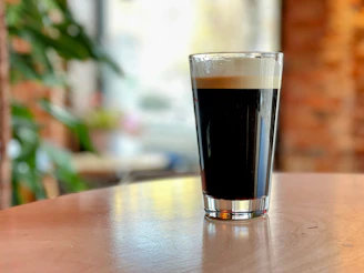 a glass of beer sitting on top of a wooden table
