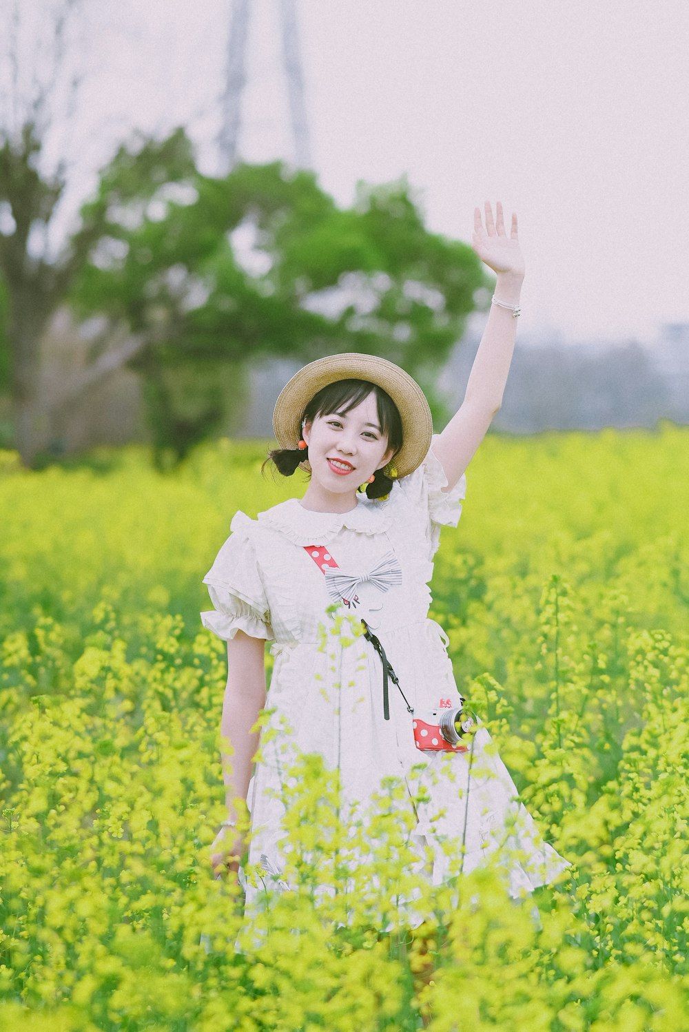 a woman in a field of yellow flowers waving
