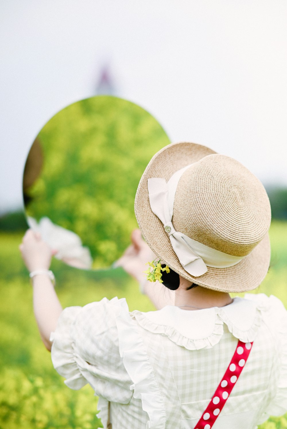a woman in a hat is holding a mirror