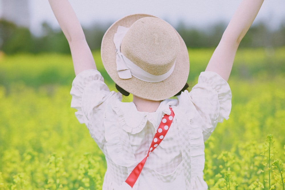 a woman in a hat is standing in a field