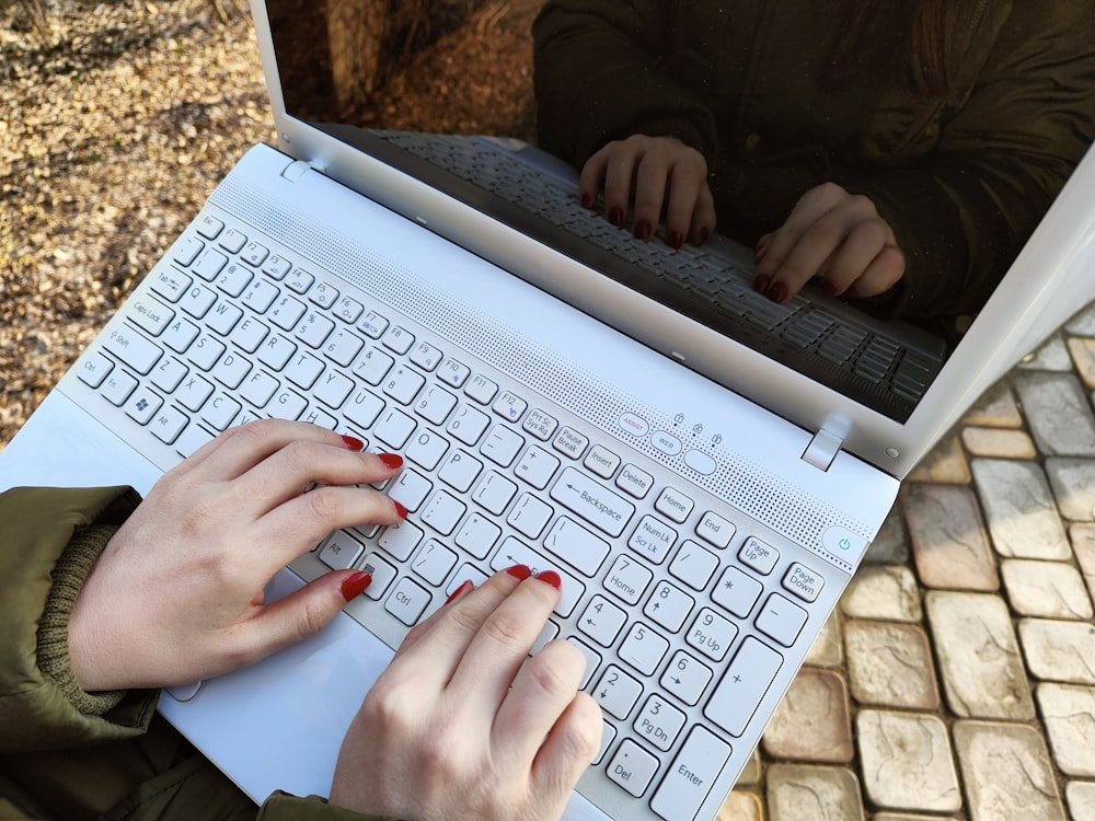 a woman is typing on a laptop outside