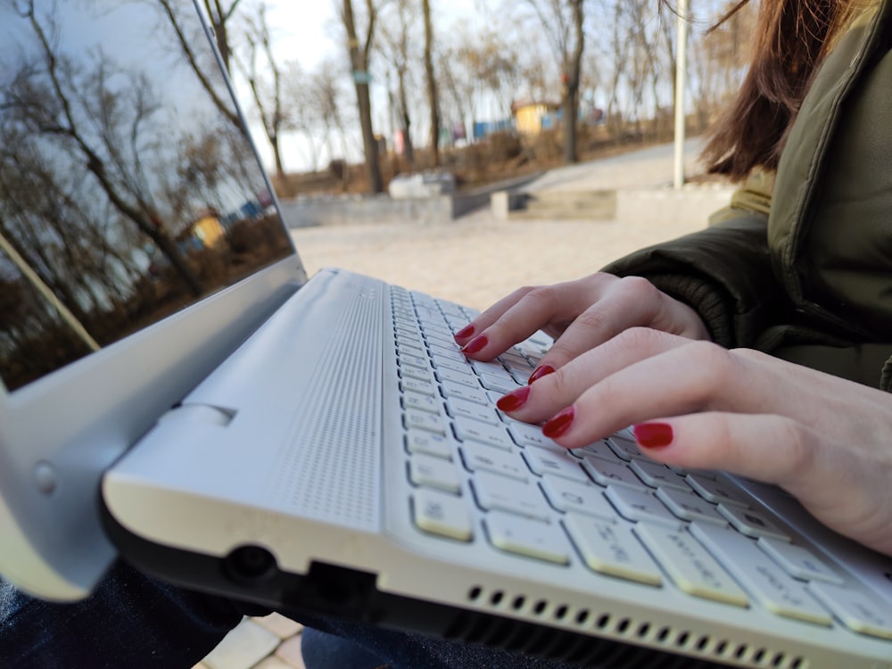 a woman is typing on her laptop outside