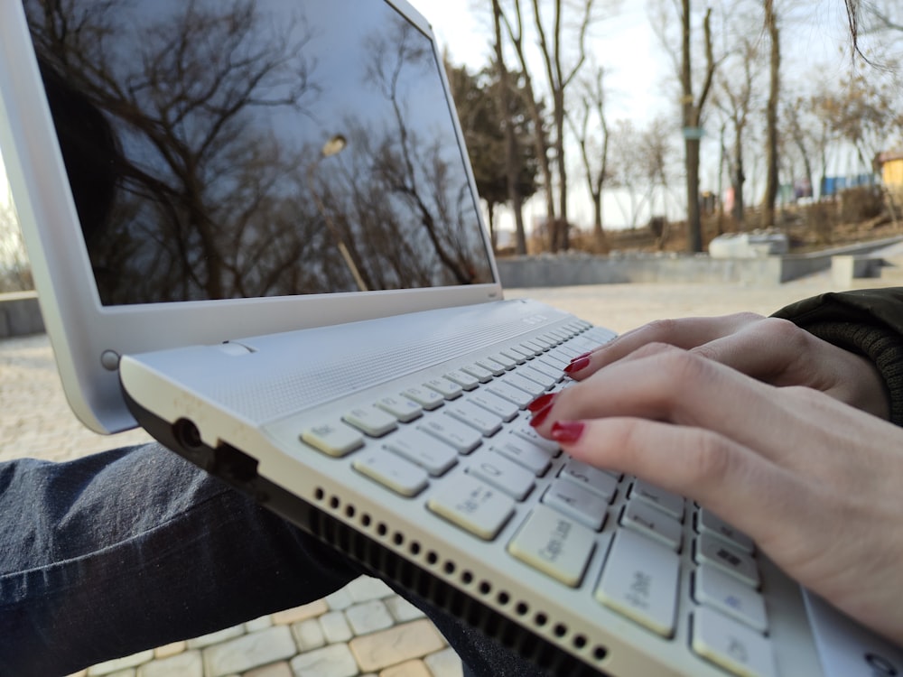 a person typing on a laptop computer outside