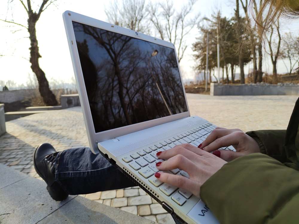 a person typing on a laptop on a bench