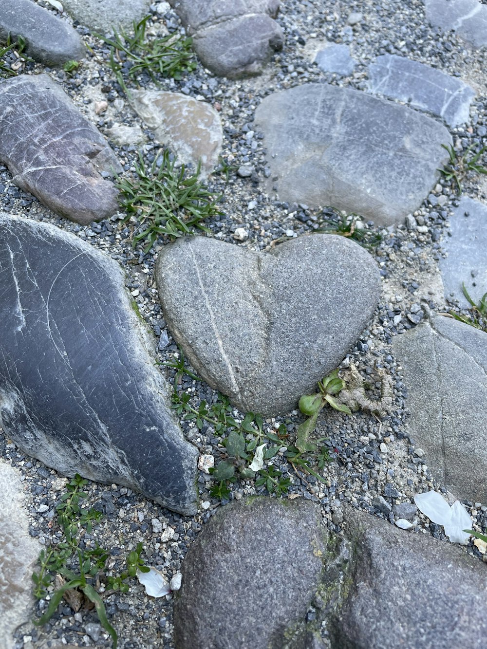 a heart shaped rock sitting on top of a gravel field
