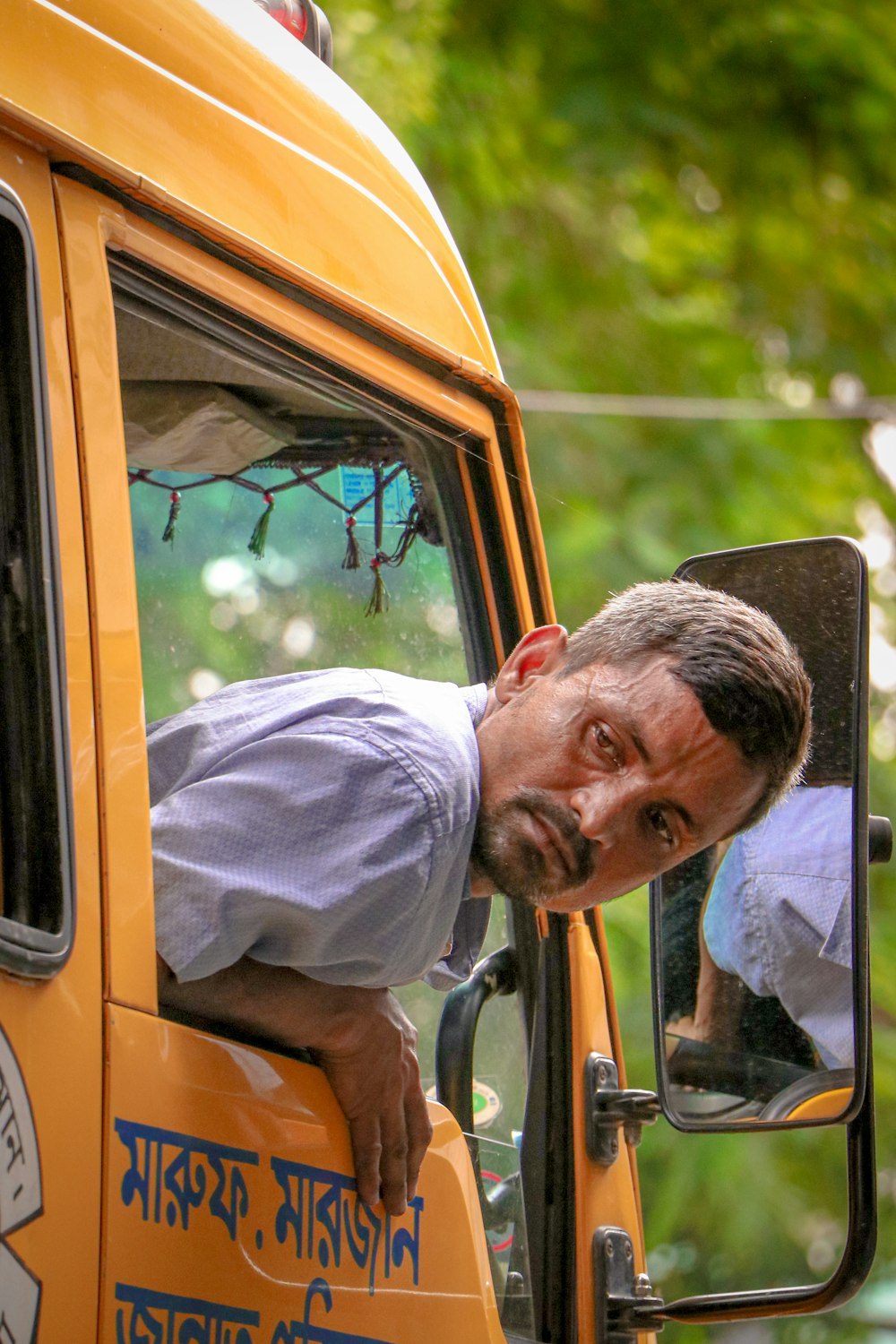 a man leaning out the window of a yellow truck