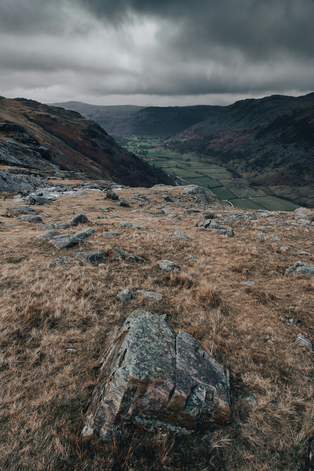 a large rock sitting on top of a dry grass covered hillside