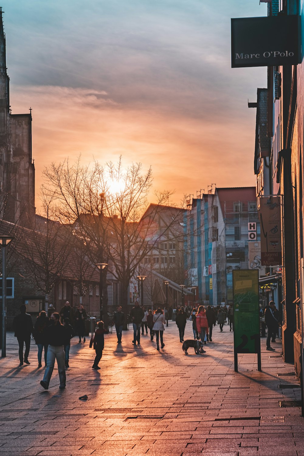 a group of people walking down a street next to tall buildings