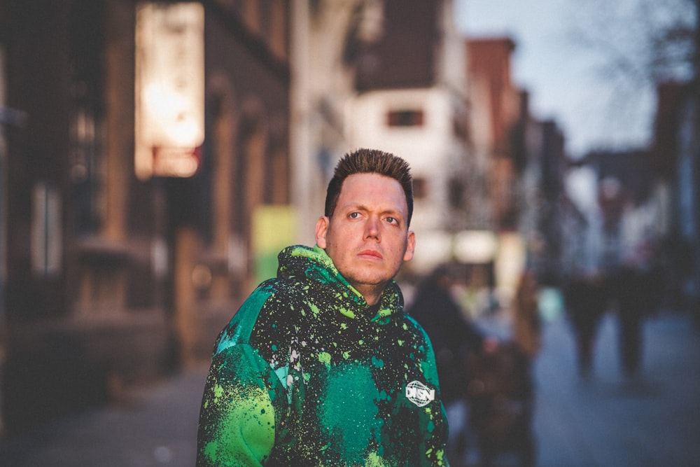 a man in a green jacket standing on a sidewalk