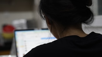 a woman sitting in front of a laptop computer