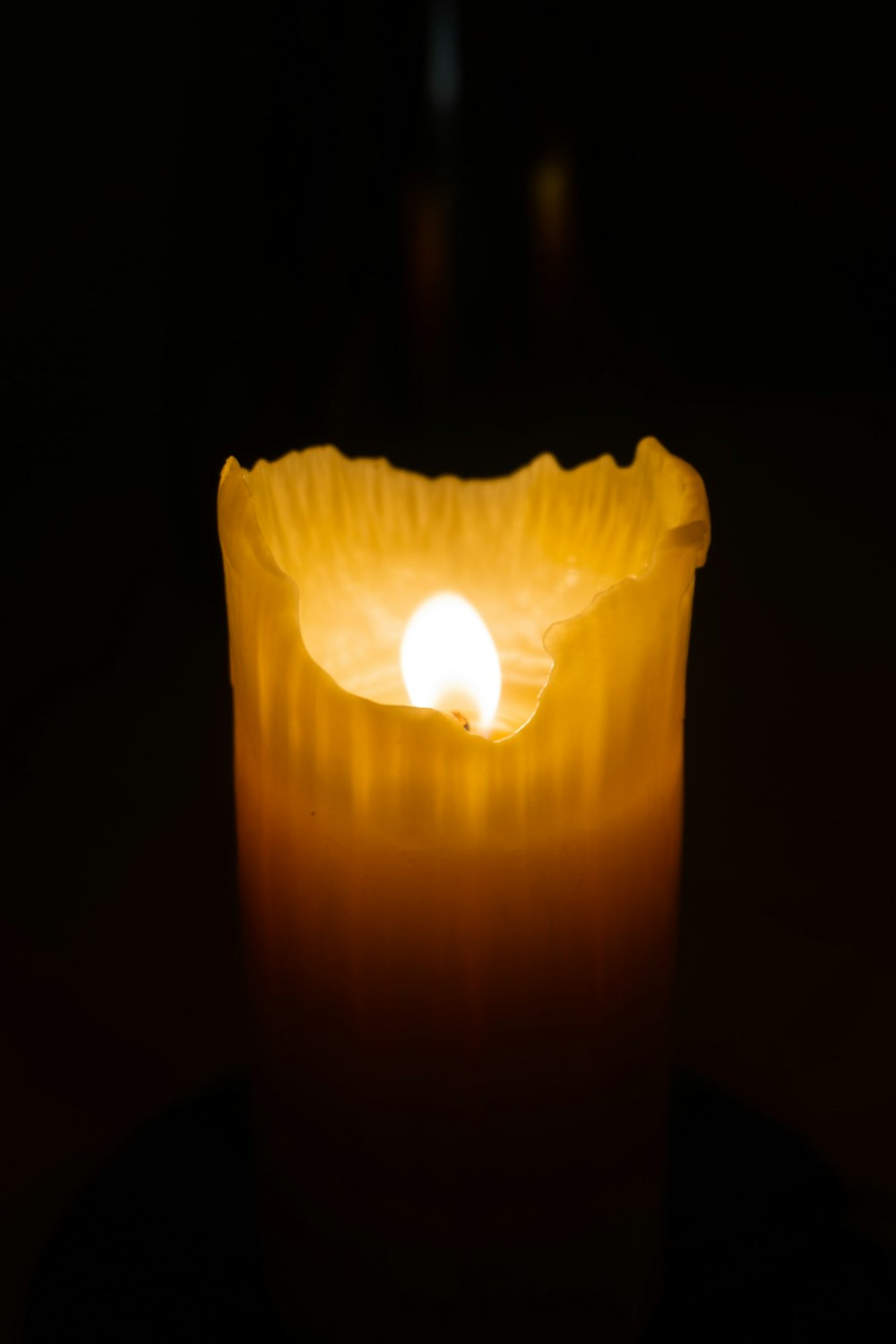 a lit candle with a dark background