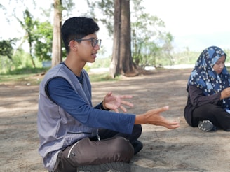 two people sitting on the ground with their hands open