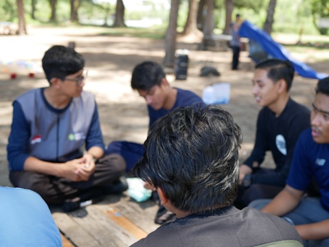 a group of young men sitting on top of a wooden bench