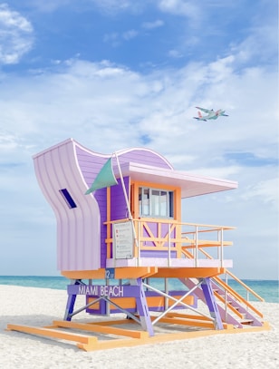 a lifeguard stand on the beach with a plane in the background