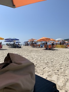 A vibrant picnic mat spread on sandy beach with a family enjoying a sunny day.