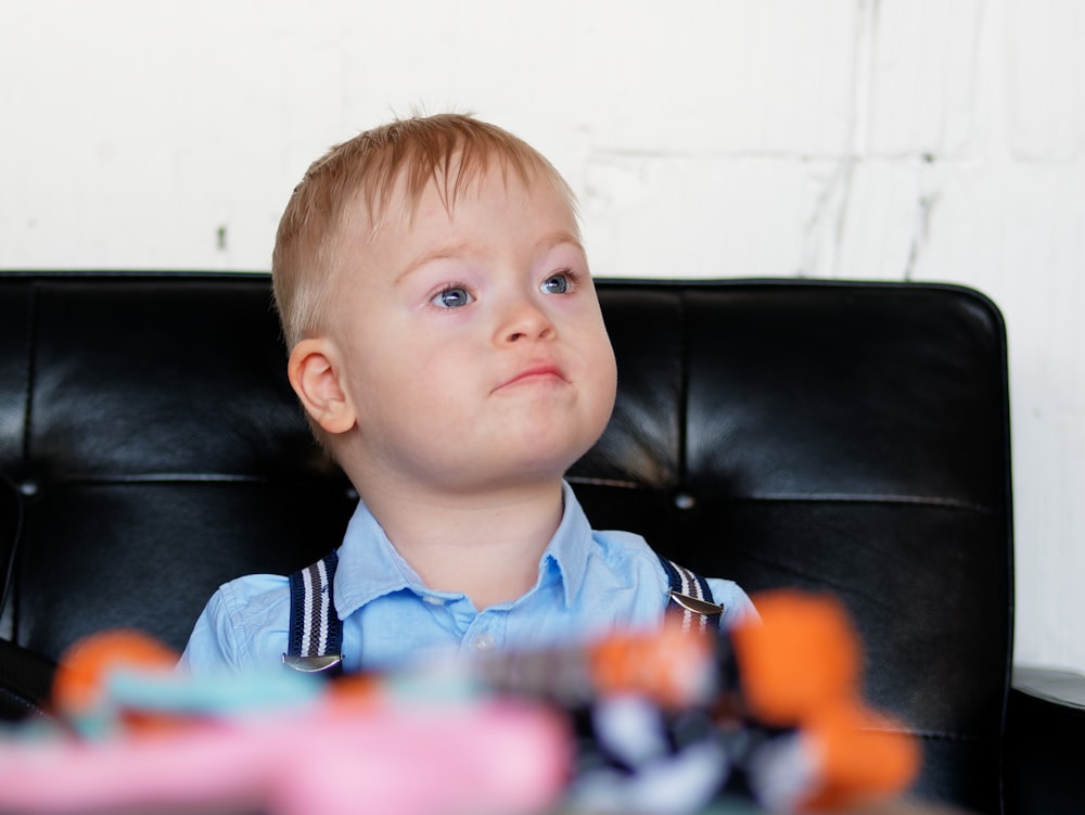 a young boy sitting in a black chair