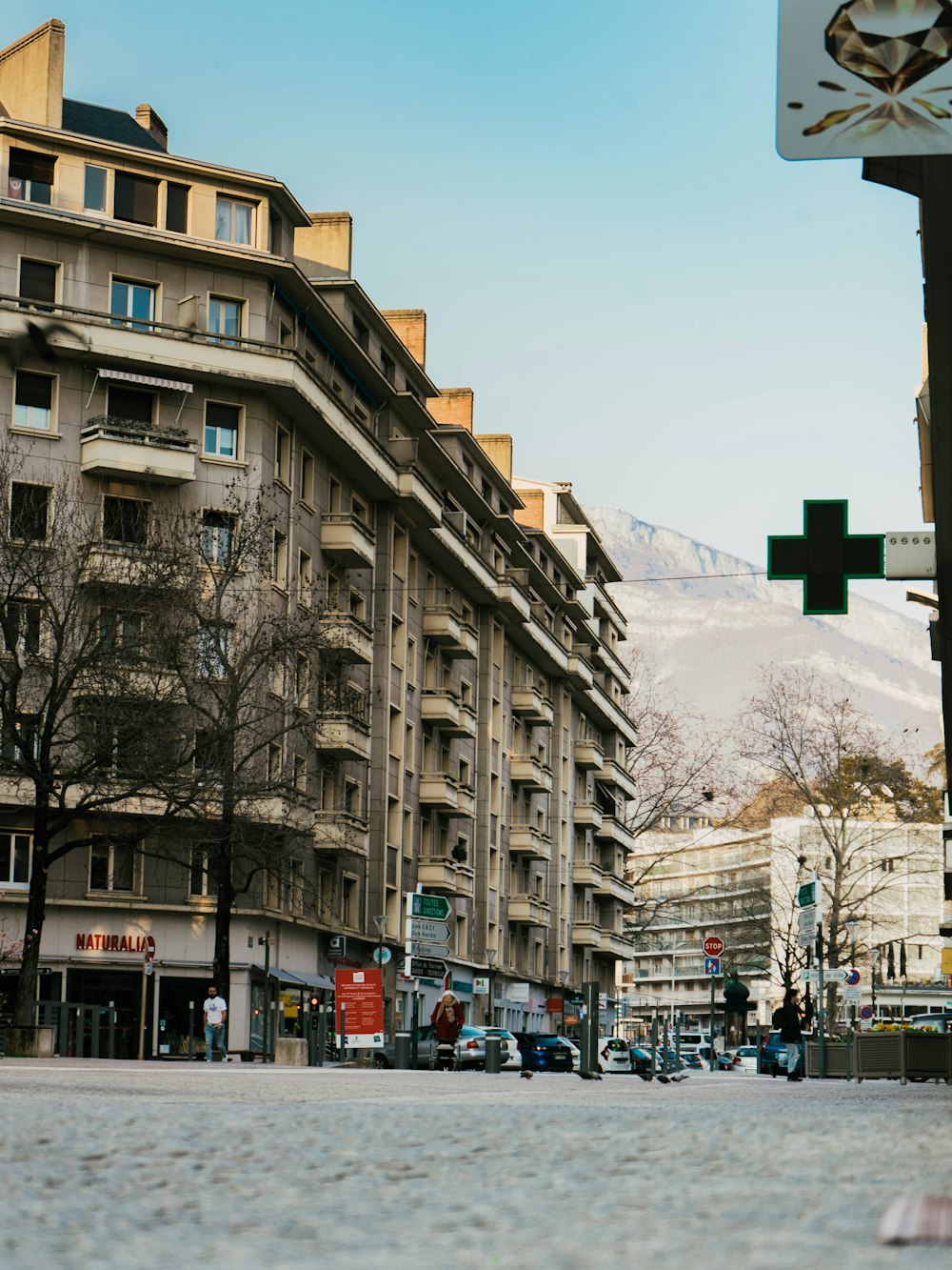 a city street with buildings and a cross sign