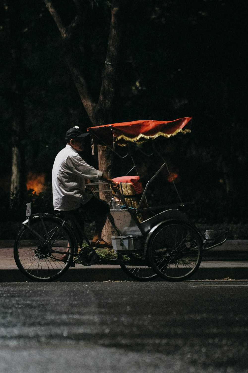 a man riding a bike down a street next to a tree