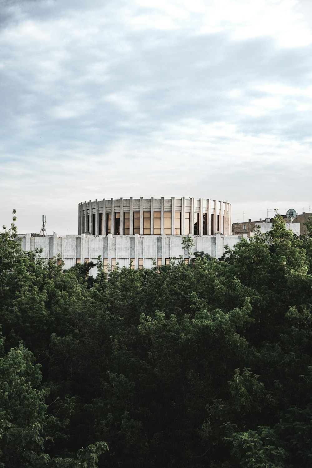 a tall building surrounded by trees under a cloudy sky