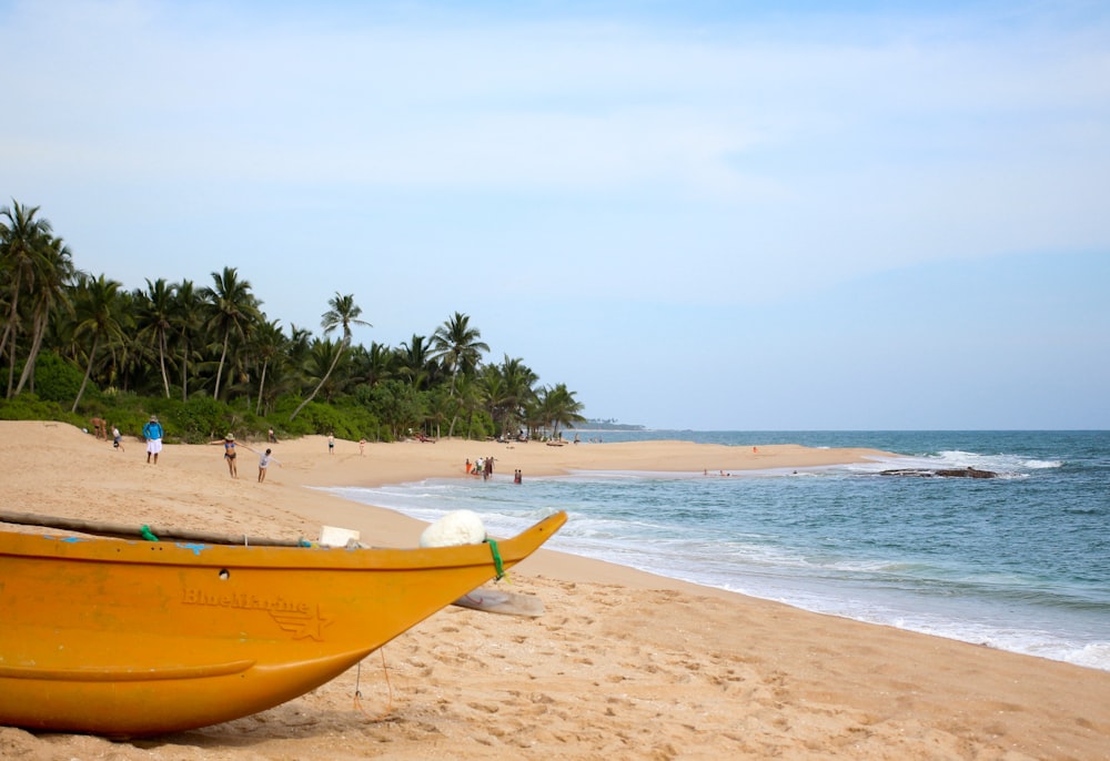 a yellow boat sitting on top of a sandy beach