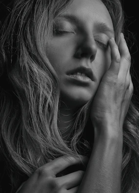 A soft-focus photo of a person smiling quietly, eyes closed, embracing a moment of self-compassion.