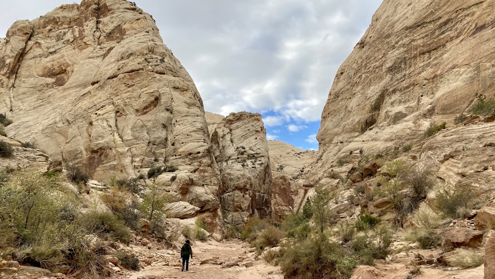 a person walking down a dirt path between two large rocks