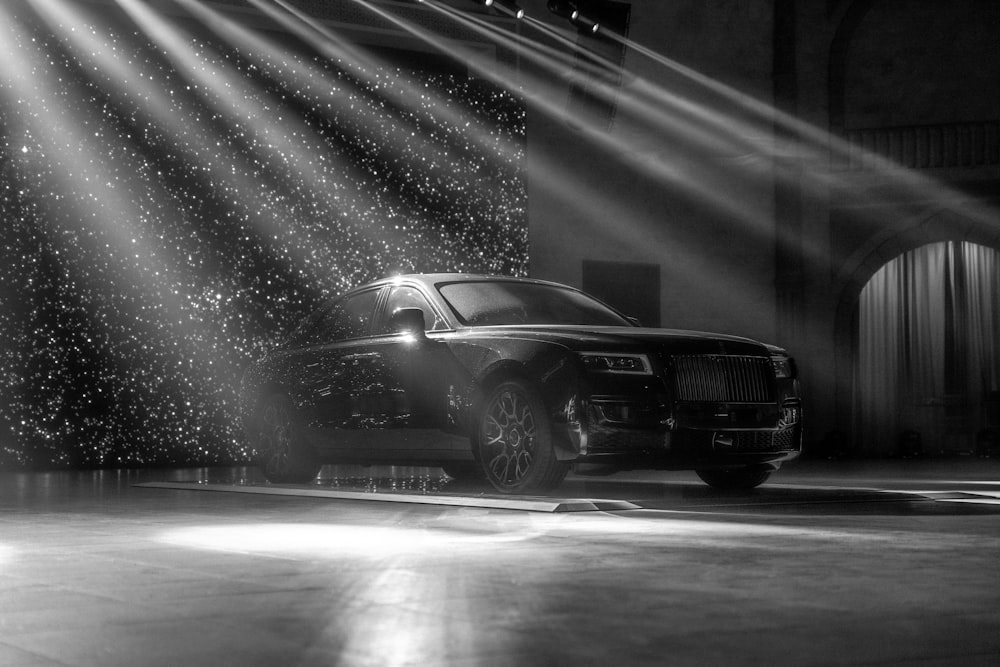 a black and white photo of a rolls royce parked in a garage