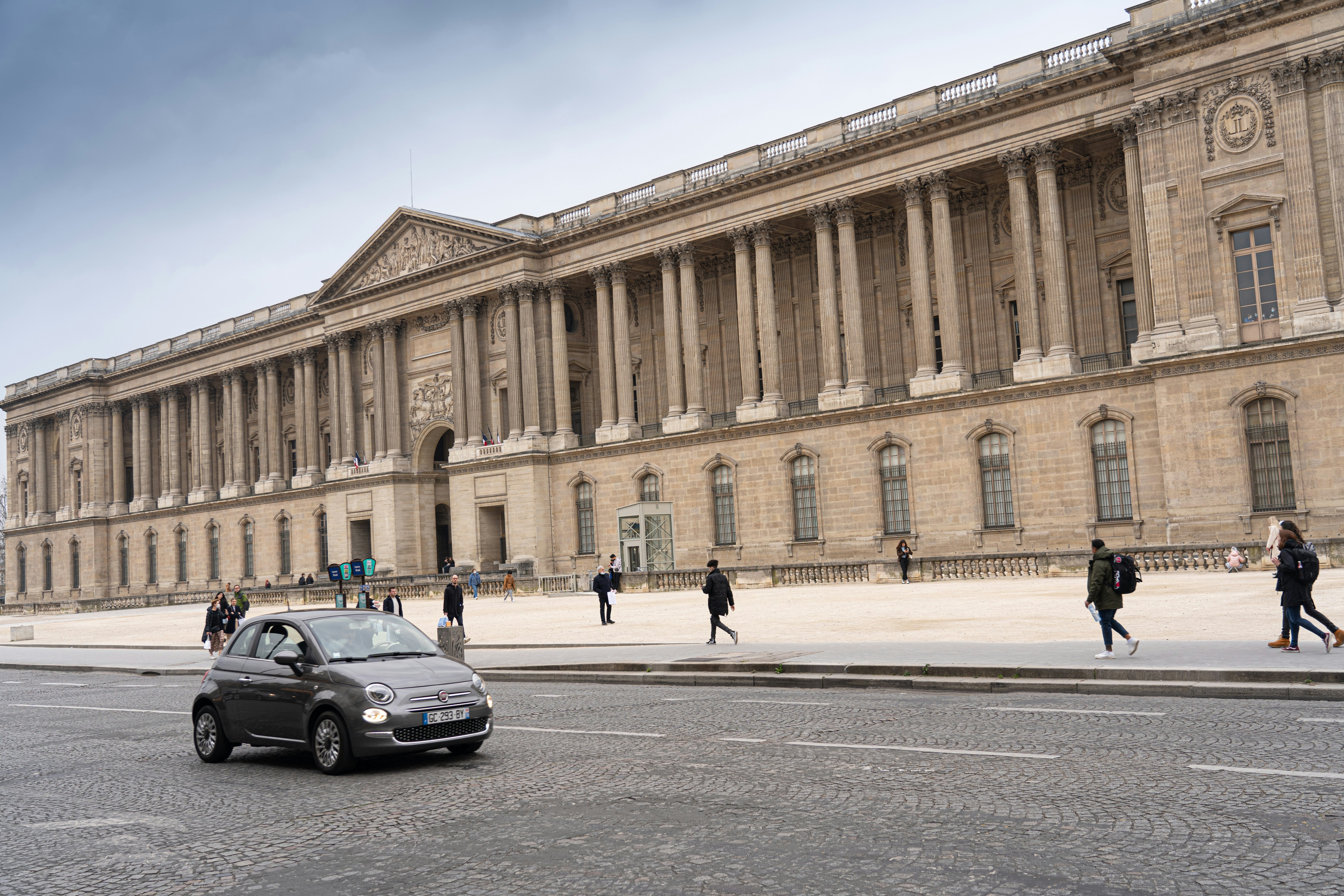 Una piccola auto è parcheggiata di fronte a un grande edificio