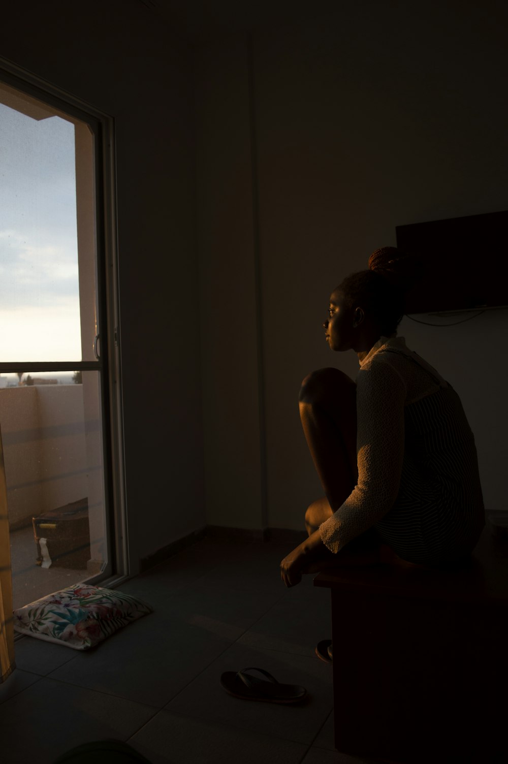 a woman sitting on a chair looking out a window