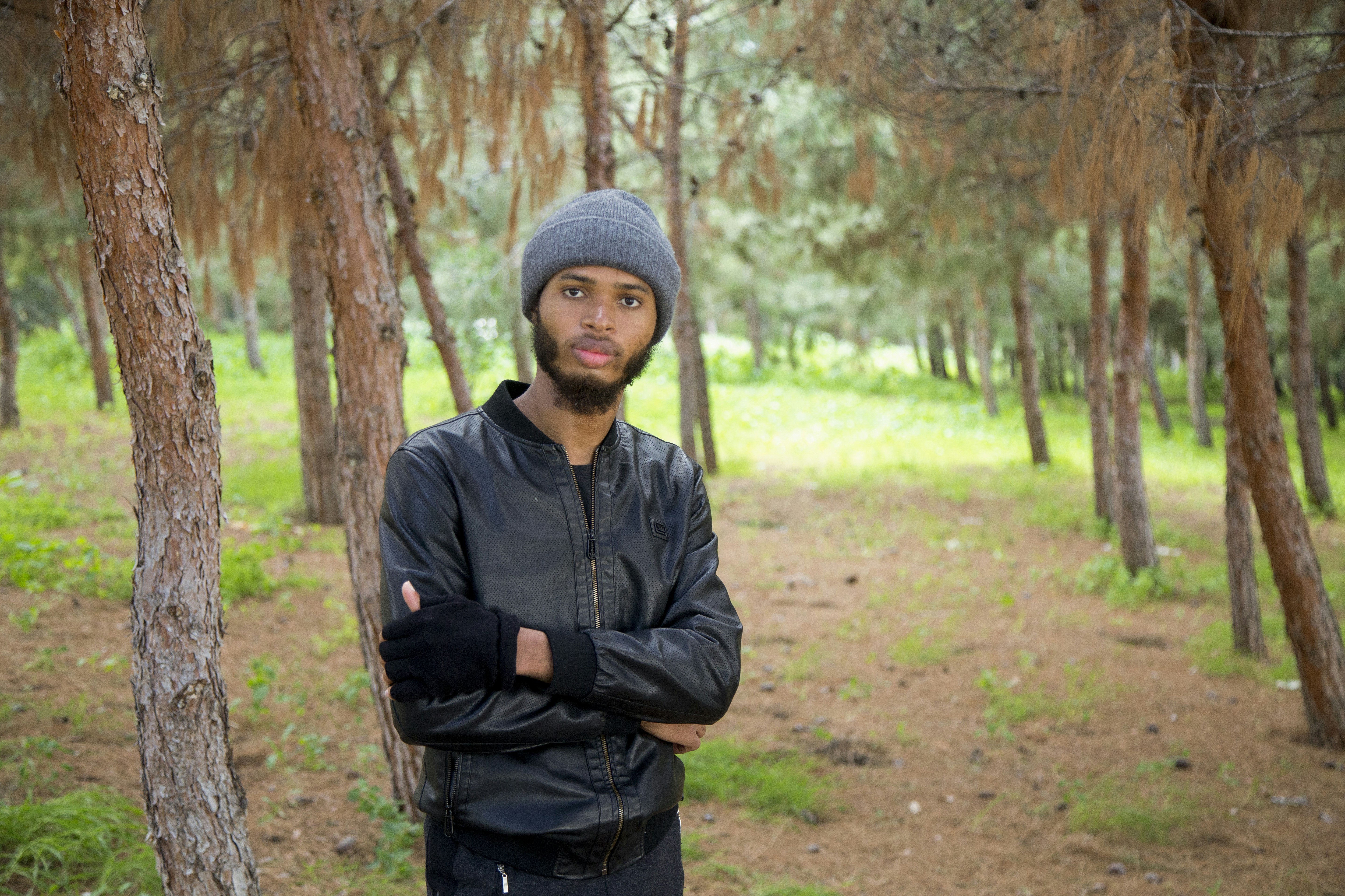 a man standing in a forest with his arms crossed