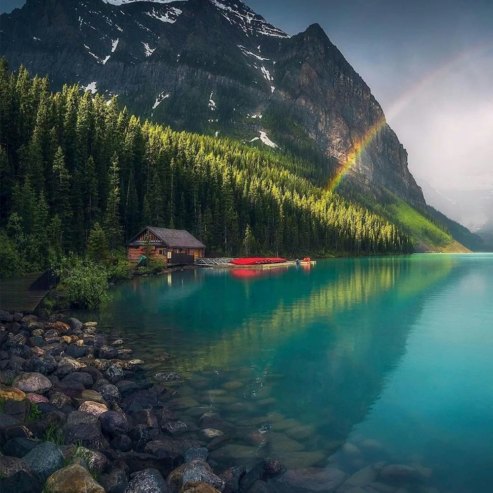 a rainbow shines in the sky over a mountain lake