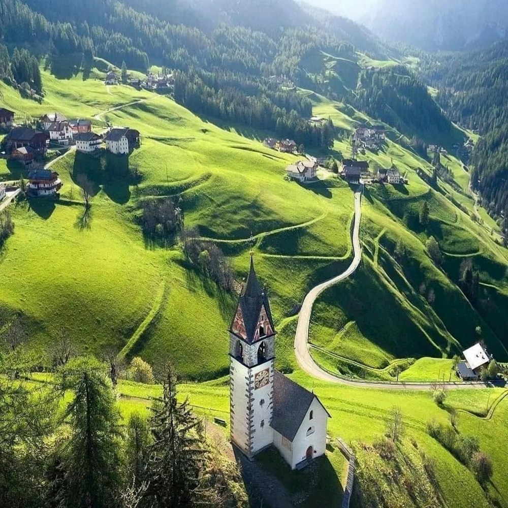an aerial view of a church in the middle of a green valley