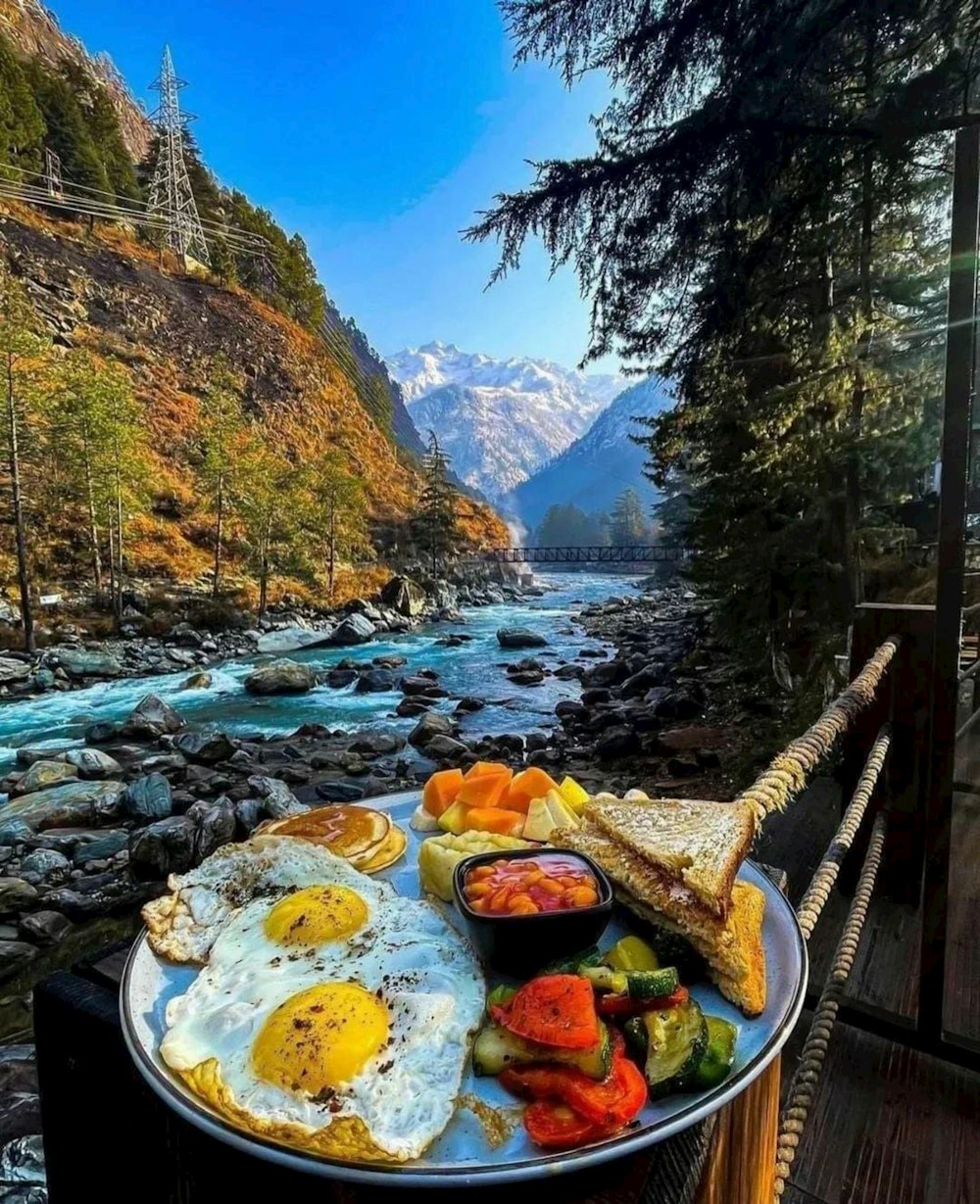 a plate of food sitting on top of a table next to a river