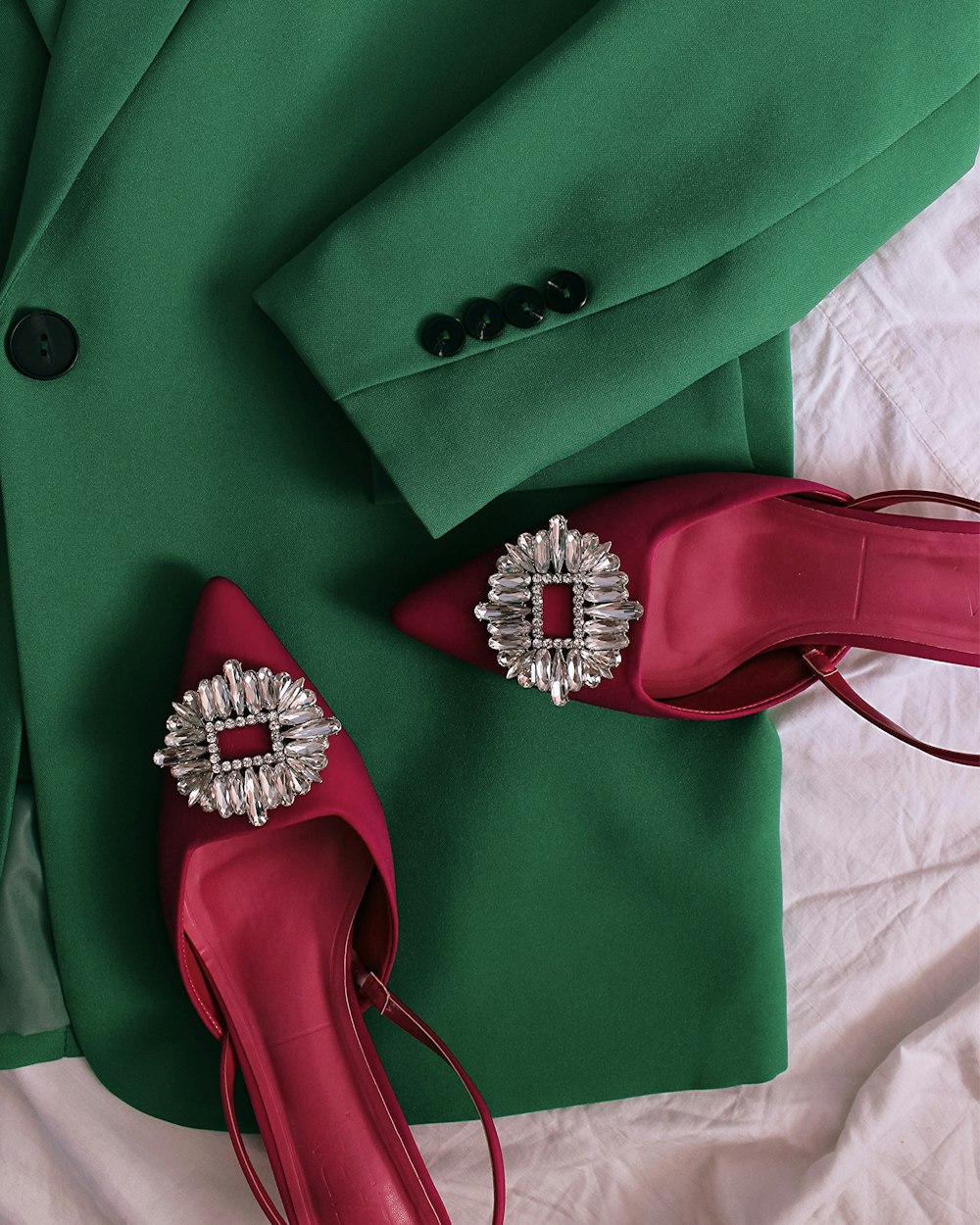 a pair of red high heels sitting on top of a green jacket