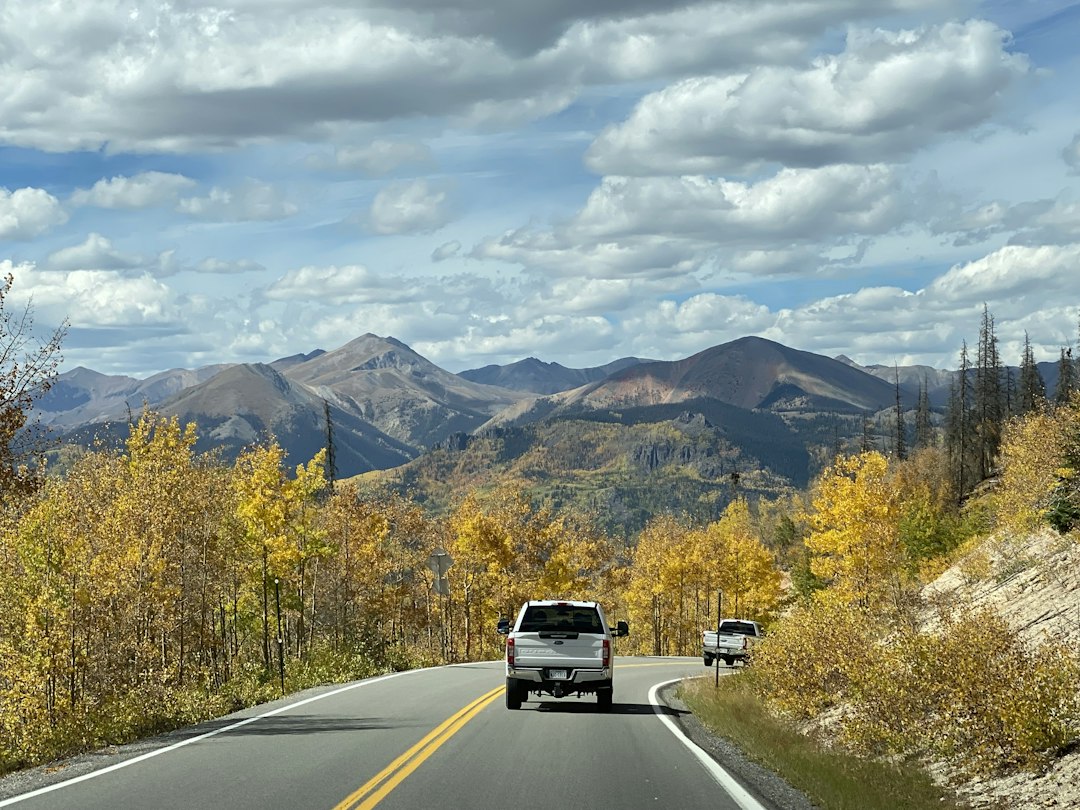 a truck driving down a road with mountains in the background,