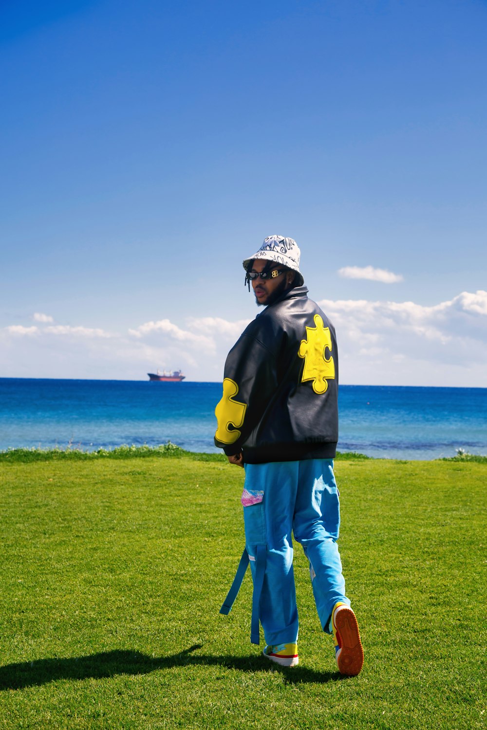 a man in a black and yellow jacket standing in the grass