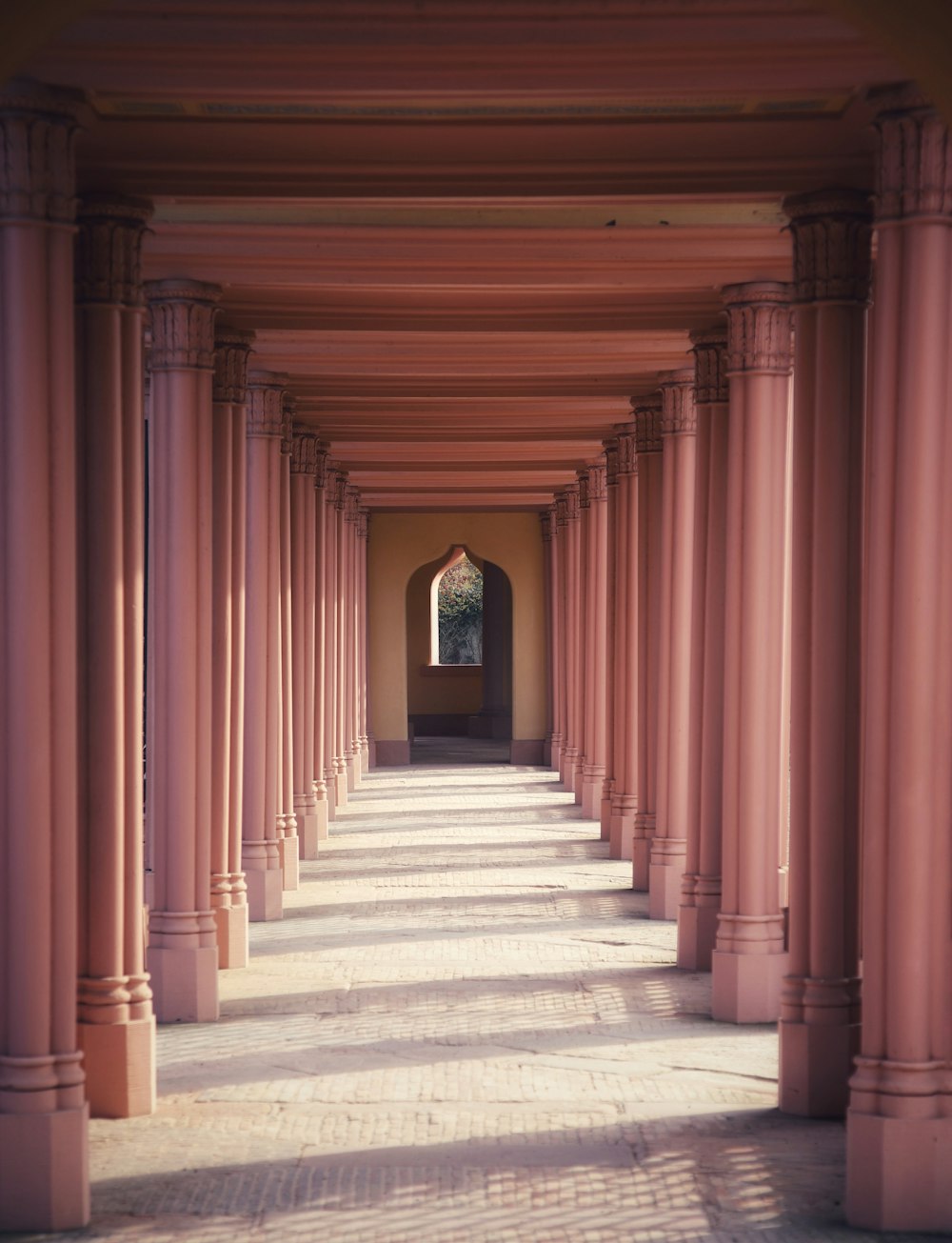 a long hallway with columns and a clock on the wall