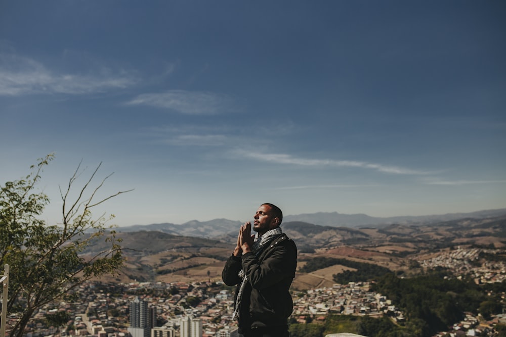 a man standing on top of a hill next to a tree