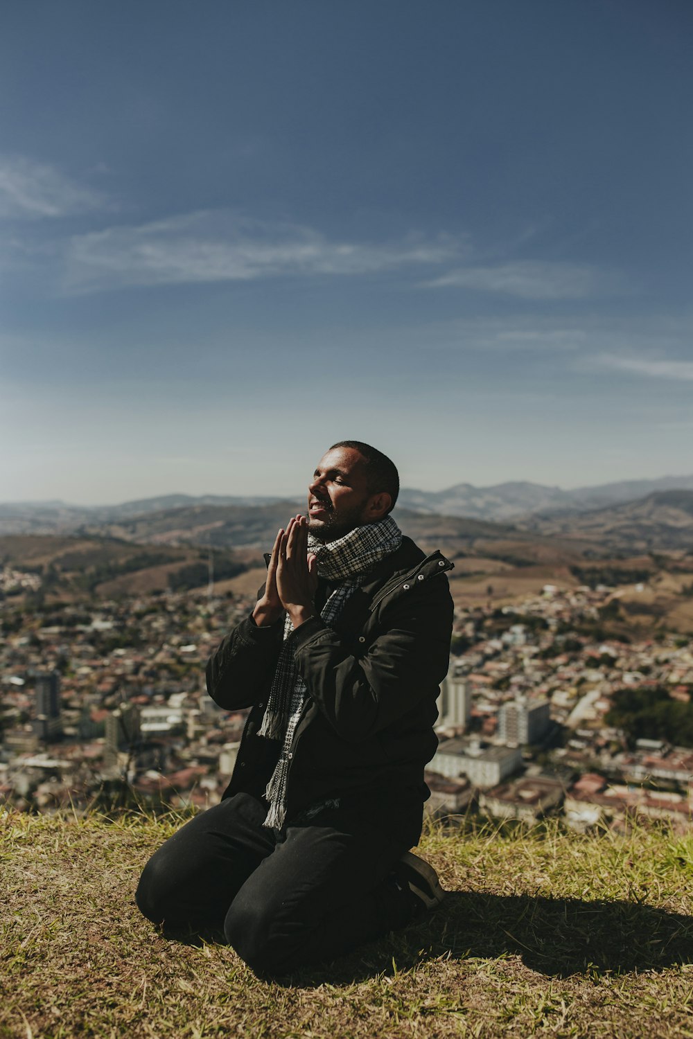 a man sitting on a hill talking on a cell phone