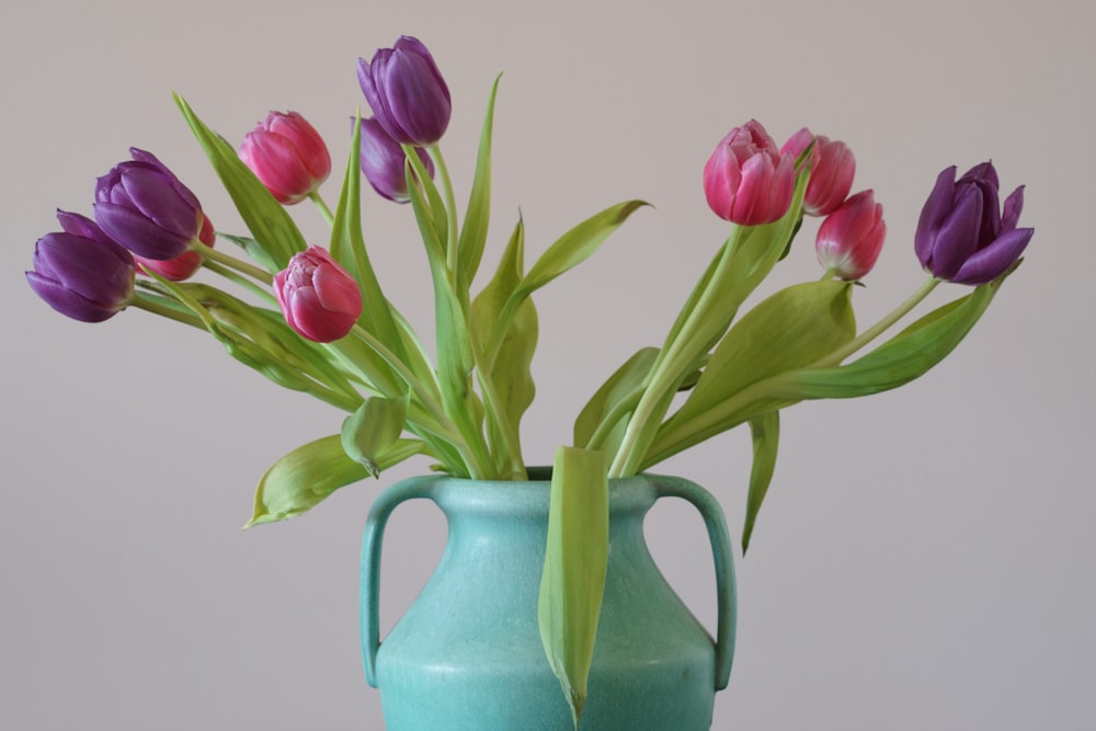 a blue vase filled with purple and pink tulips
