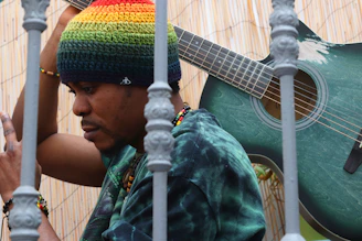 a man with a rainbow hat holding a guitar