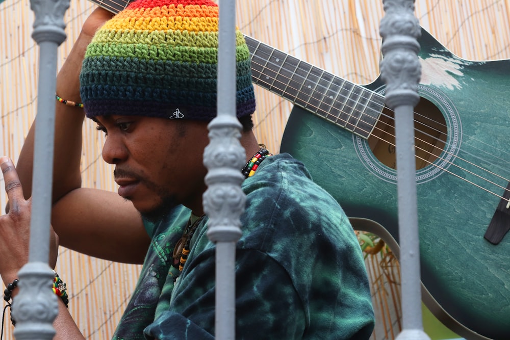 Un hombre con un sombrero de arco iris sosteniendo una guitarra