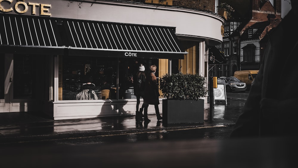 a woman standing outside of a store on a rainy day