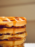 A stack of fluffy pistachio waffles drizzled with syrup.