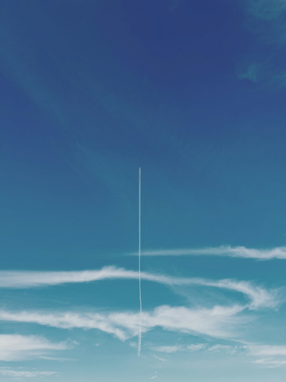 Ein Flugzeug fliegt am Himmel mit einem Kondensstreifen im Hintergrund